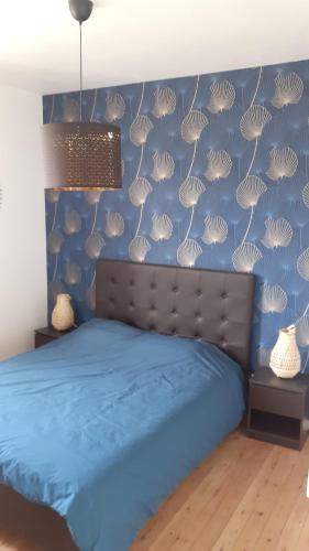 Un dormitorio con una cama con una pared azul con conchas en Gîte de la Filature 