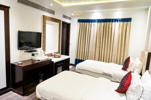 a hotel room with two beds and a television at Hotel Grand Godwin - Free Airport Pick-Up in New Delhi