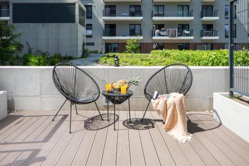 two chairs and a table with drinks on a patio at Rent like home - River City Apartments in Wrocław