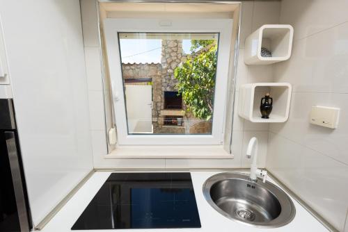 baño con lavabo y ventana en Apartments Viky, en Kraljevica