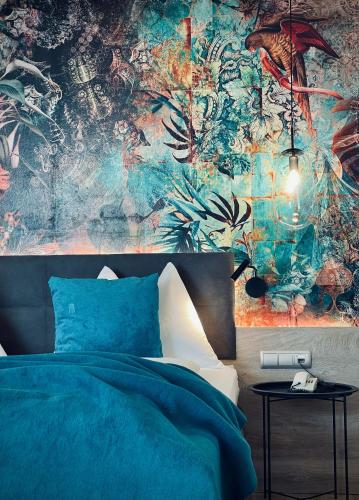 a bedroom with a blue bed and a colorful wall at Landhotel Schwabenhof in Heiligenbrunn