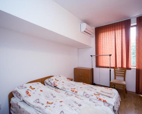 a bedroom with a bed and a chair and a window at ALEKS Top Center in Burgas