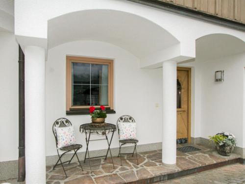 patio z 2 krzesłami i stołem z kwiatami w obiekcie Apartment Kohler by Interhome w mieście Fügen