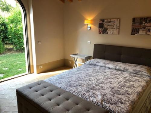 a bedroom with a large bed with a large window at Piccolo Borgo Gagnoni in Sinalunga