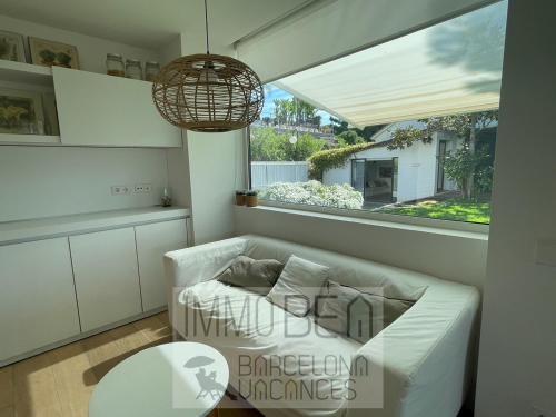 sala de estar con sofá blanco y ventana en BARCELONAVACANCES SV-001-PARAISO en Caldes d'Estrac