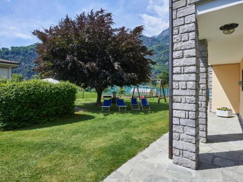 a yard with two blue chairs and a tree at Apartment Serena - LMZ180 by Interhome in Riva
