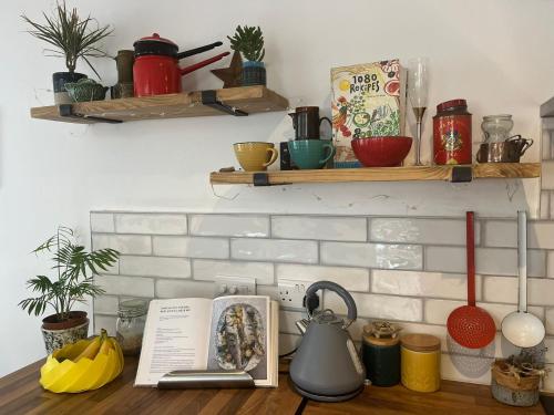 a kitchen counter with a tea pot and a book at Beach, hills, food, scenic walks-The Kelp house. in Peacehaven