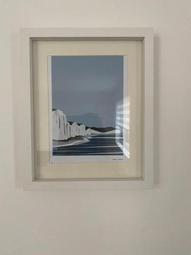 a picture in a white frame on a wall at Beach, hills, food, scenic walks-The Kelp house. in Peacehaven