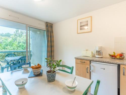 cocina y comedor con mesa y balcón en Apartment Village Cheval Spa Résidences-4 by Interhome, en Lacanau-Océan