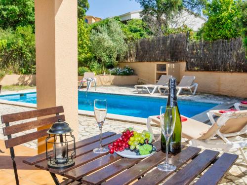 a wooden table with a plate of fruit and wine glasses at Holiday Home Mas Pere by Interhome in Calonge