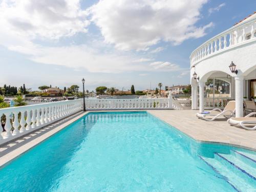 a swimming pool with chairs next to a building at Holiday Home Peni by Interhome in Empuriabrava