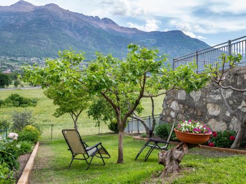 a garden with two chairs and a tree and a pot of flowers at Apartment Cima by Interhome in Aosta