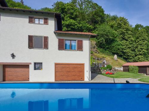 ein Haus mit zwei Garagentüren und einem Pool in der Unterkunft Holiday Home Letizia by Interhome in Cresciasca