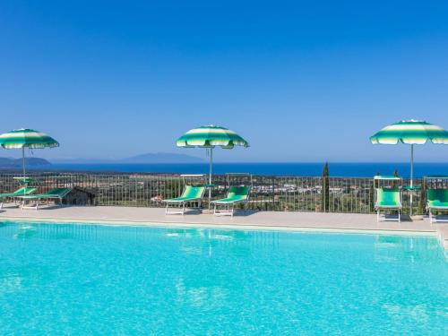 einen Pool mit grünen Stühlen und Sonnenschirmen in der Unterkunft Holiday Home Il Corbezzolo-2 by Interhome in San Vincenzo