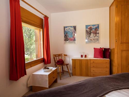 Schlafzimmer mit einem Bett, einem Schreibtisch und einem Fenster in der Unterkunft Apartment Chesa Pra d`Sura 217-10 by Interhome in Maloja