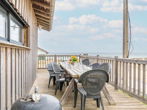 a dining table and chairs on a deck with the beach at Holiday Home Les Mouettes by Interhome in Mimizan-Plage