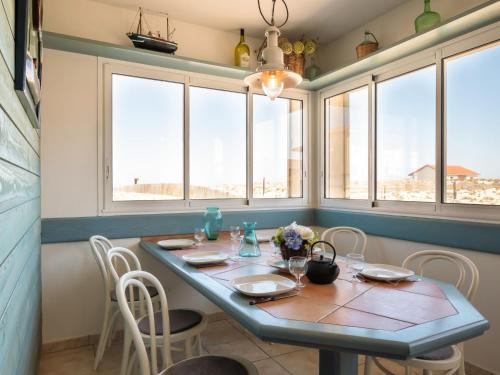 a dining room with a table and chairs and windows at Holiday Home Villa Marine by Interhome in Mimizan-Plage