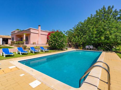 a swimming pool with blue chairs and a house at Holiday Home Isaurinda by Interhome in Faro