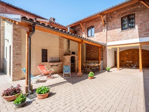 eine Terrasse mit Stühlen und einem Tisch in einem Backsteingebäude in der Unterkunft Apartment La Quercia by Interhome in Mondovì