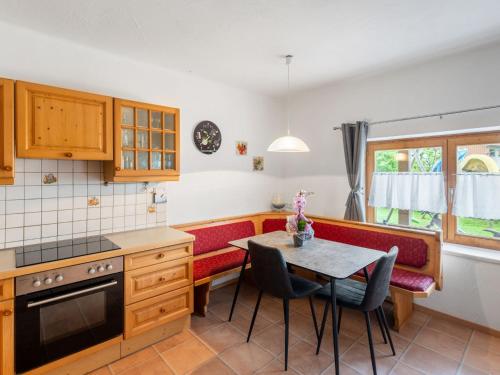 uma cozinha com uma mesa e bancos vermelhos e uma mesa e cadeiras em Holiday Home Marion by Interhome em Saalfelden am Steinernen Meer