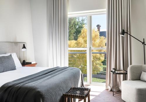 a bedroom with a bed and a chair and a window at Cleveland Estate in Lancefield