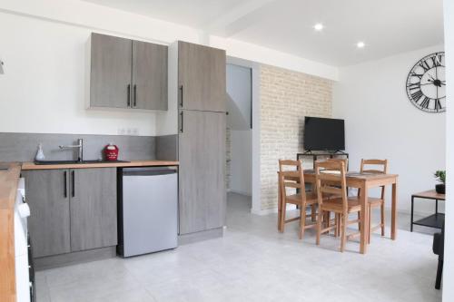 una cocina con armarios de madera y una mesa con sillas. en Le temps d'une pause''', 