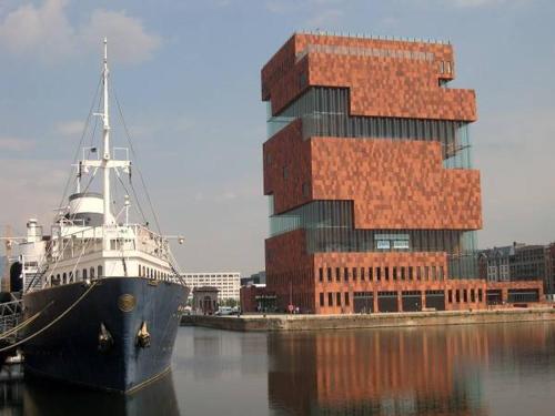 a boat sitting in the water next to a building at On our way to Antwerp, first stop in Mortsel