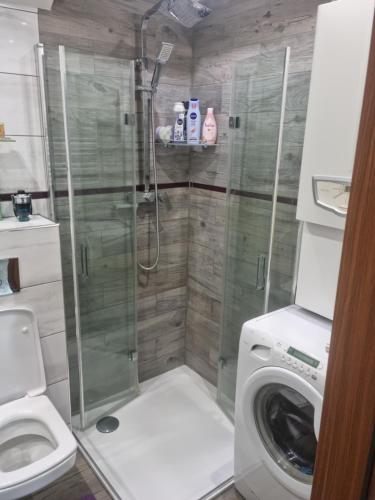 a bathroom with a shower and a washing machine at Apartament Baszta Kaszana in Trzebiatów