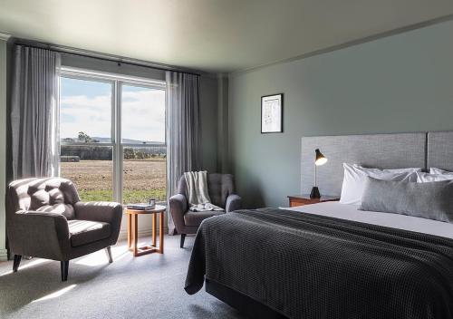 a bedroom with a bed and two chairs and a window at Cleveland Estate in Lance Field