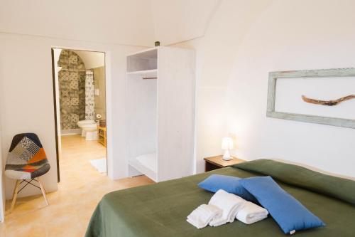 a bedroom with a green bed and a bathroom at Il Mulino di Scauri in Pantelleria