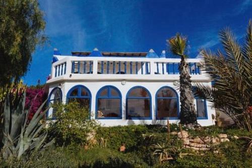 una casa bianca con una palma di fronte di Room in Guest room - Room in villa Lair De La Mer a Sidi Kaouki