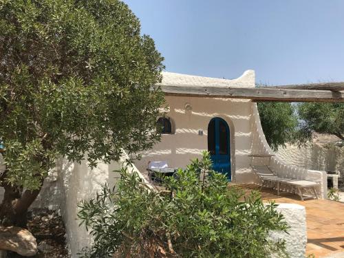 a white house with a blue door and trees at Villette di Cala Creta in Lampedusa