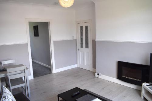 a living room with white walls and a fireplace at Kelpies Serviced Apartments - Wallace in Falkirk