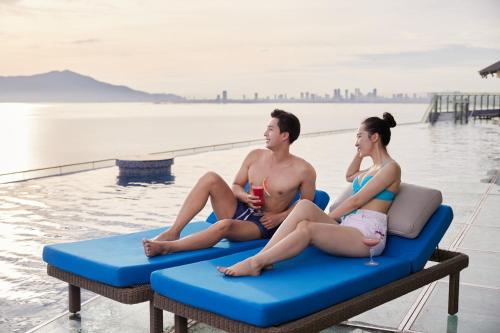 a man and a woman sitting on a raft in a pool at Da Nang - Mikazuki Japanese Resorts & Spa in Da Nang
