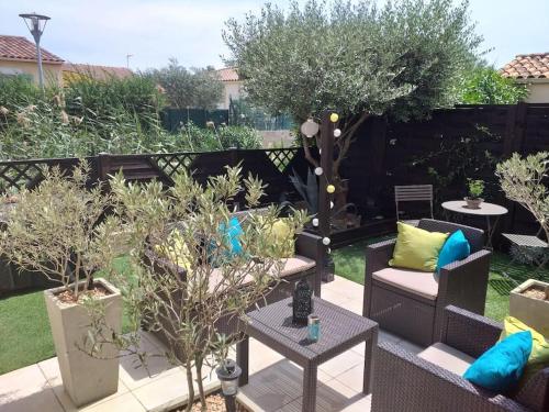 un jardín con 2 sillas, mesa y árboles en Chambre à 500 m des remparts, en Aigues-Mortes