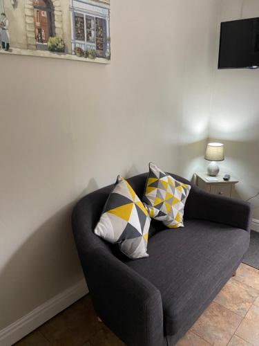 a black couch with two pillows in a living room at Linden Tree Holiday Apartments in Thirsk