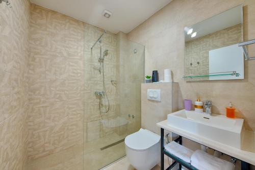 a bathroom with a shower and a toilet and a sink at Sunset hotel & beach in Dobra Voda