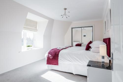 a white bedroom with a large bed and a table at Roomspace Serviced Apartments - Royal Swan Quarter in Leatherhead
