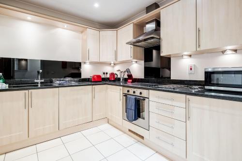 a kitchen with white cabinets and black counter tops at Roomspace Serviced Apartments - Royal Swan Quarter in Leatherhead