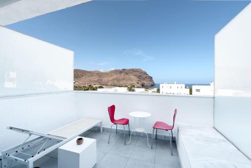 a white room with a table and two red chairs at Hotel Spa Calagrande Cabo de Gata in Las Negras