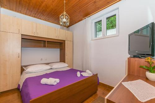 a bedroom with a bed and a flat screen tv at Apartments Josip in Makarska