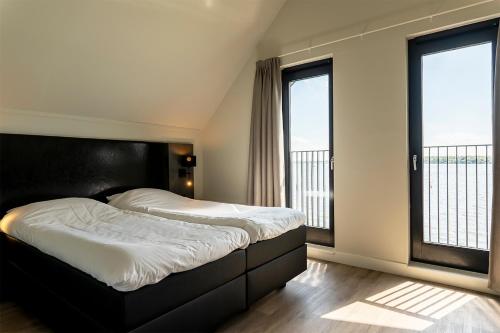 a bedroom with two beds and two windows at Baayvilla's in Lauwersoog