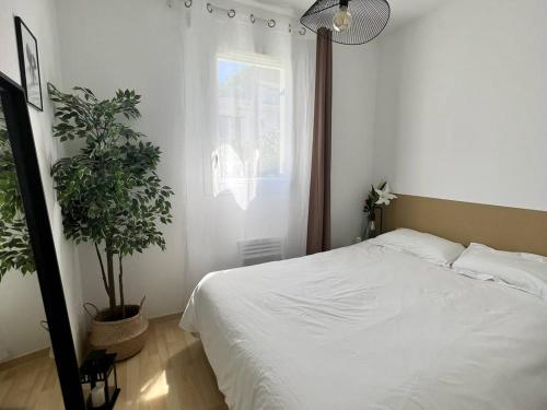 1 dormitorio con cama blanca y maceta en Appartement Cambo-les-Bains, 1 pièce, 2 personnes - FR-1-495-105, en Cambo-les-Bains