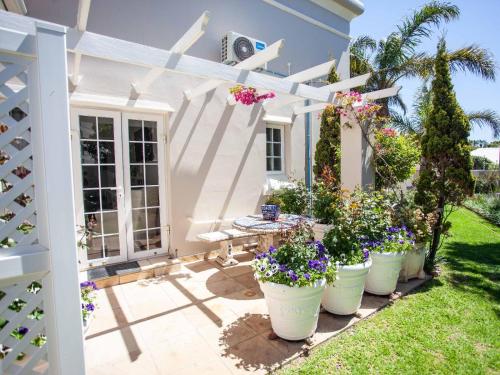 a patio with potted plants and a white pergola at No 4 Boutique Beach House in Summerstrand