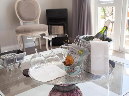 a glass table with a bottle of wine and wine glasses at No 4 Boutique Beach House in Summerstrand