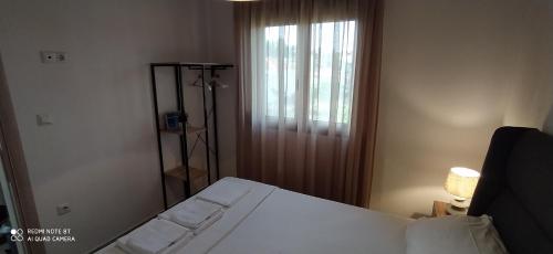 a bedroom with a white bed and a window at Lavender and Sea in Nea Potidaea