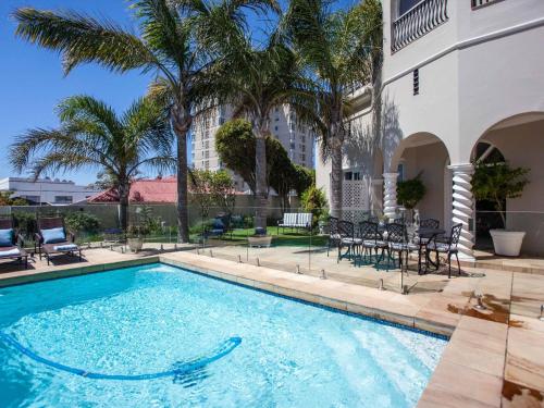 a swimming pool with chairs and a building at No 4 Boutique Beach House in Summerstrand