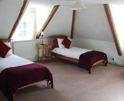 two beds in a room with two windows at Sarum College in Salisbury