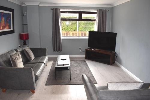 uma sala de estar com um sofá e uma televisão de ecrã plano em 3 Bedroom-Kelpies Serviced Apartments Bruce em Falkirk