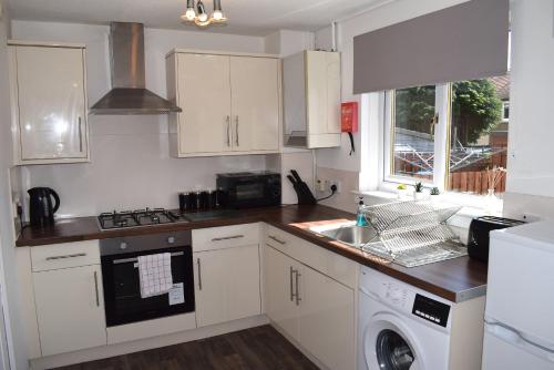 a kitchen with white cabinets and a dishwasher at Kelpies Serviced Apartments-McKay in Falkirk